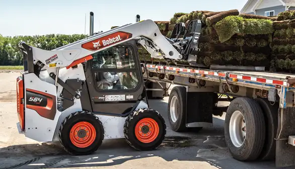 Bobcat skid-steer loader unloading sod with pallet forks